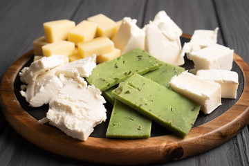 Close up cheese plate. White, yellow and green cheeses. Healthy food. Natural cheeses slices. Side view.