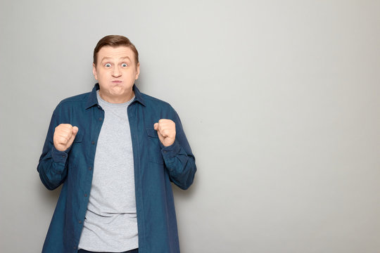 Portrait of excited man raising clenched fists in anticipation