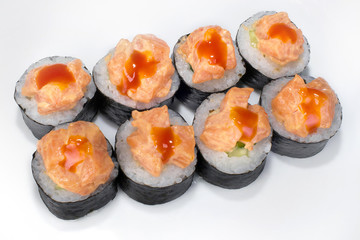 Traditional Japanese roll of rice, nori seaweed, shrimp and scrambled eggs with spicy sauce on a white plate