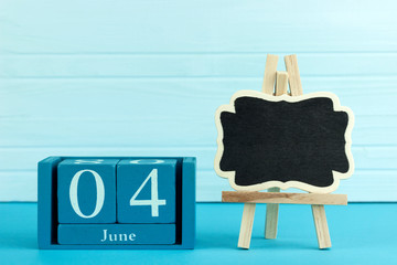 wooden calendar with the date of June 4 and an easel on a blue background, place for text,International Day of Innocent Children Victims of Aggression, World Caries Day