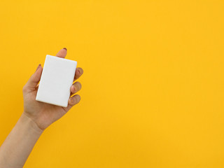 hand holding a white soap on yellow background