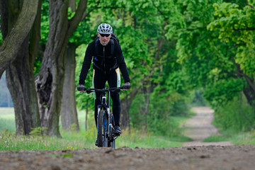 A man on a bicycle riding on a forest path.