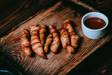 chicken sticks with sauce on a wooden board