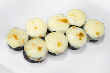 Baked Japanese roll of rice, mussels, spinach with cream, mozzarella and sesame seeds on a white background