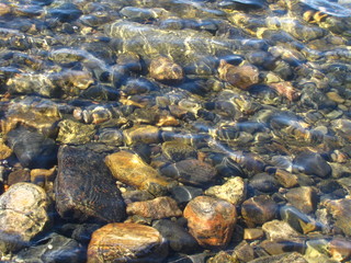 Sea ​​stones under water with glare of the sun on the surface 
