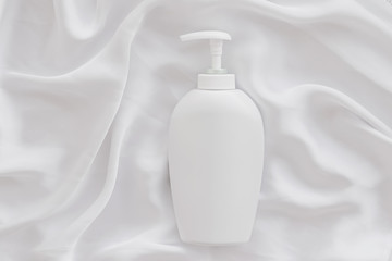Blank label cosmetic container bottle as product mockup on white silk background, hygiene and...