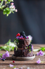 Chocolate cake with blackberry and other flowers on wooden table