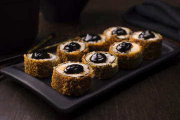 Traditional salmon fish hot roll with tare sauce in a black platter in wood background