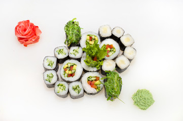 Vegetable set of vegetable rolls of rice, nori, cucumbers, avocado, tomato, seaweed, ginger, wasabi on a white background