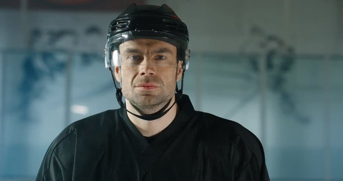Portrait shot of handsome young Caucasian male hockey player in helmet looking at camera with seious face on ice arena. Close up of attractive sportsman in casque.