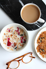 Organic granola breakfast with raspberries, coffee, and almond milk. Lifestyle flat lay with white background
