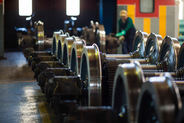 Axles with wheels of railway cars lie in a row at a repair plant - obrazy, fototapety, plakaty