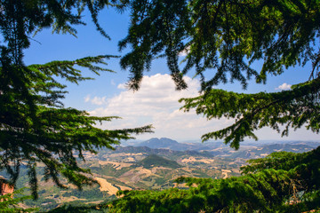 Fototapeta na wymiar View of the mountains of San Marino through green pine branches