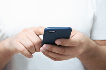 A person is holding a phone and tapping the screen on a white background with copy space. Concept of lifestyle business and Internet technologies in the office