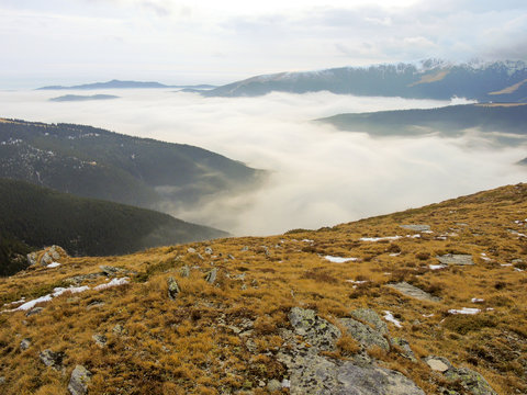 clouds forming alpine sea over iezer papusa mountains romania in a cold autumn day