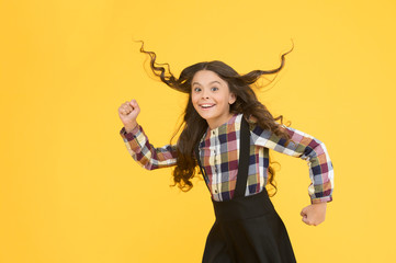 Make haste slowly. Energetic girl hurry to school. Small child wear long hairstyle yellow background. Back to school hairstyle. Hair salon. Fashion hairstyle. School look. Great hairstyle every day