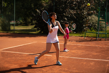 a mother and daughter playing tennis outdoors and having fun