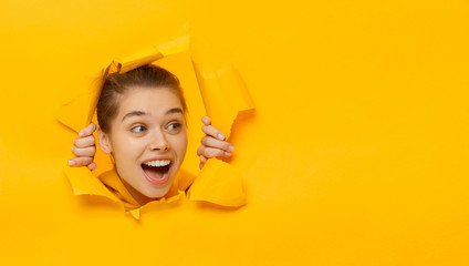 Horizontal banner of young female tearing paper and peeking out hole, curious about commercial...