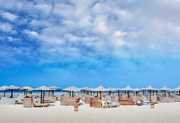 Empty beautiful clean beach with sunbeds and umbrellas, Egypt. Vacation concept. View of the beach with umbrellas and palm trees