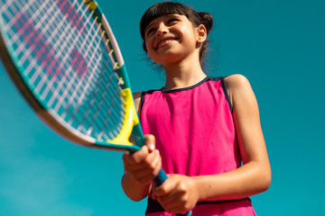 petite fille jouant au tennis sous un ciel bleu