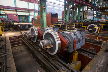 Fototapeta na wymiar Axles with wheels of railway cars lie in a row at a repair plant