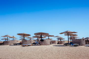 Empty beautiful clean beach with sunbeds and umbrellas, Egypt. Vacation concept. View of the beach with umbrellas and palm trees