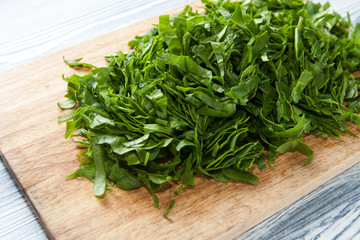 Chopped spinach on a wooden cutting board. Dietary nutrition. Close-up, selective focus