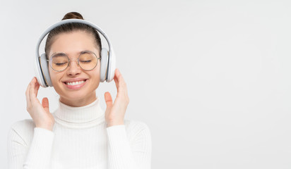 Banner of young woman in glasses and wireless headphones, smiling happily with eyes closed,...