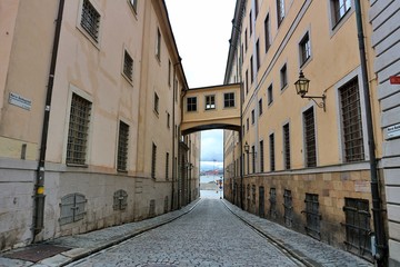 Fototapeta na wymiar Stockholm / Sweden - 7 May 2020: Narrow alley with window bridge connecting buildings in gamla stan empty no people deserted