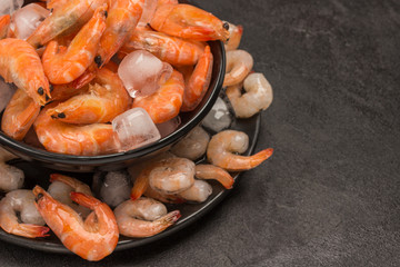 Tiger prawns and shrimp in black plate with ice.