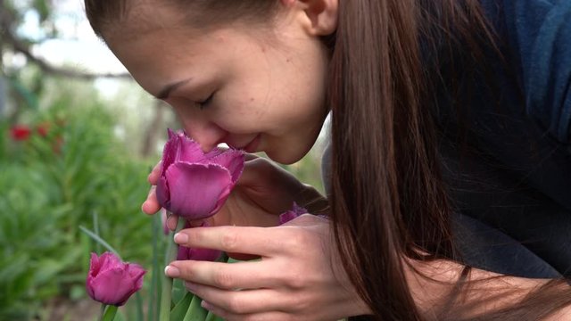 Young brunette tender romantic woman smeling purple tulips In garden