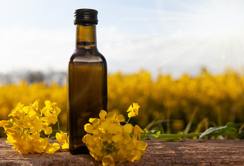 Rape oil and flower on wooden table with nature rape field background.