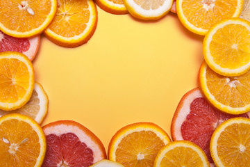 Flat lay slices of fresh orange, grapefruit and lemon formed a frame on a orange background. Bright...