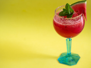 Watermelon cocktail on yellow background. Fresh watermelon with mint and ice for summer party. Refreshing.
