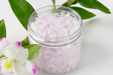 Transparent plastic jar with large flakes of violet lavender marine dead sea salt isolated on clean white background