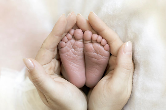 Mom Holds In Her Hands The Feet Of A Newborn Baby