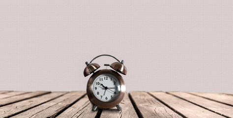 alarm clock with metal bells stands on a wooden desk in front of bright background copy space