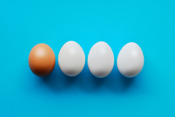 whole white eggs and one differ on the blue background, abstract vision be different, unique personality or stand out from the crowd, leadership quality.