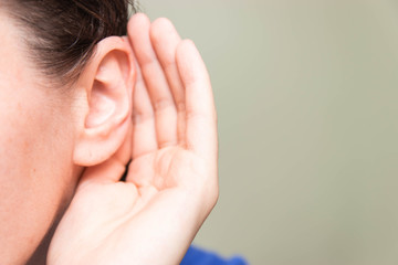 Woman holds her hand near ear and listens, close-up, indoors, the news concept