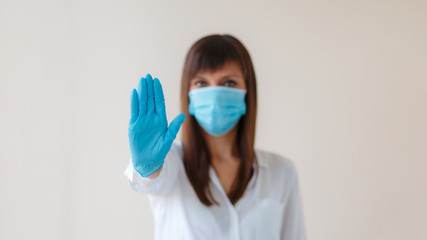 Caucasian young woman showing palm, hand, stop no sign. Wearing protective respiratory mask and gloves for prevent infection. Medical concept from outbreak Covid 19 virus, cold, respiratory disease.