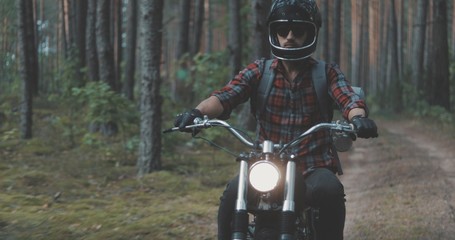 Young rider driving motorcycle on forest road