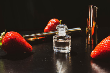 Dark vintage composition with elegant small perfume bottle and golden sticks on the dark background. Red, golden and black colours photo. Selective focus.