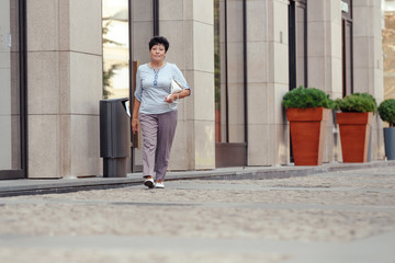Aged woman wearing casual clothes while walking on the street.