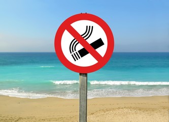 View of a no smoking sign on the beach with calm sea captured on a sunny day