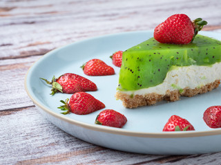 close up view to kiwi cake with strawberries on rustic table