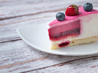 pink cake with strawberry and blueberries on white plate on the rustic table with copy space