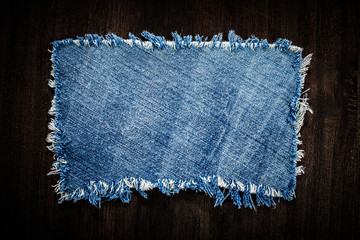 Denim blue cloth frame patch on wooden table. 
