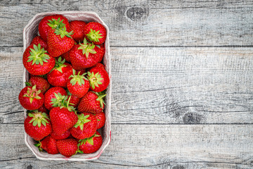 Fresh German strawberries in carton paper boxes on wooden table, top view.  Red strawberry berrees harvesting concept