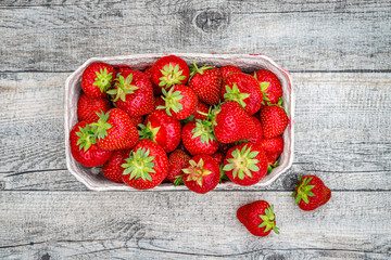 Fresh German strawberries in carton paper boxes on wooden table, top view.  Red strawberry berrees...