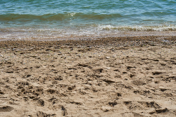 Sandy beach. Footprints of people on the sand near the water of the sea and ocean. Sunny day by the water without people.